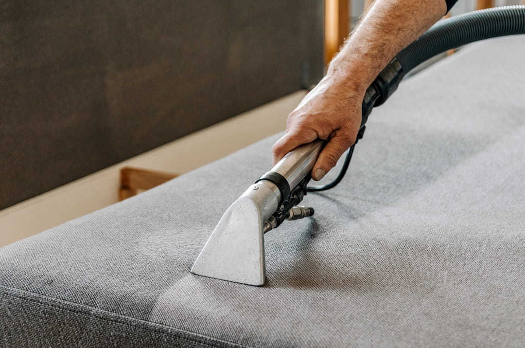 homme avec un aspirateur pour canapé et tissus